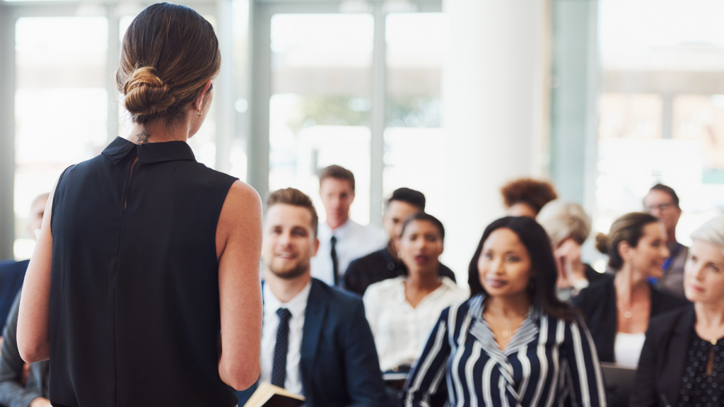 Mujer dando una ponencia frente a espectadores