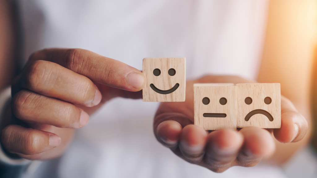 Mano sosteniendo dados con caras sonrientes y tristes